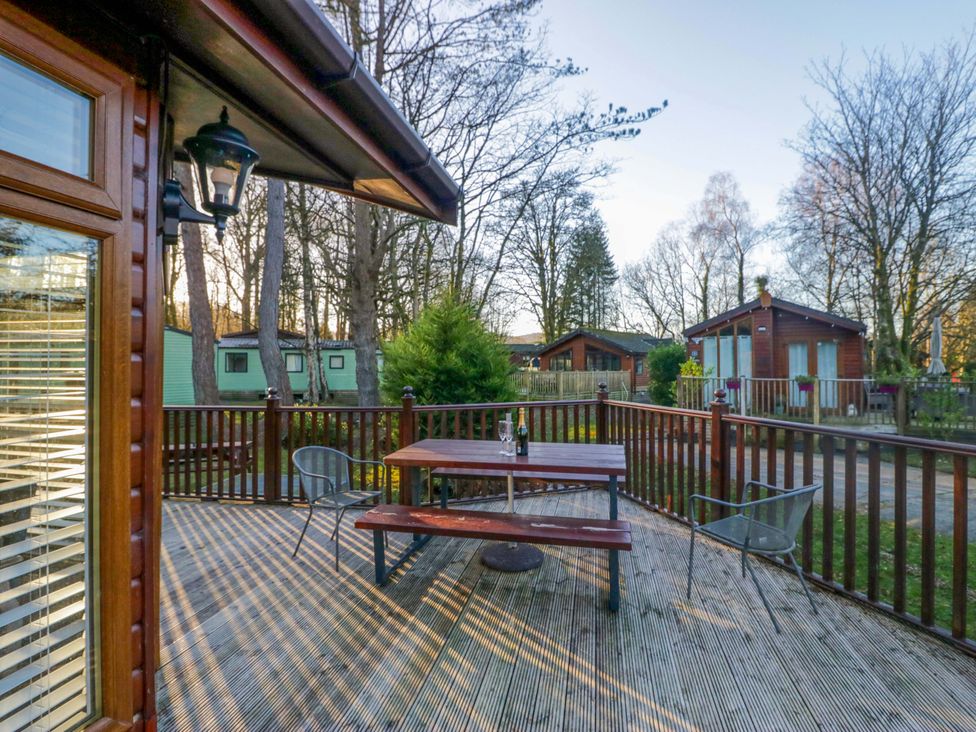 An outdoor space with a table and chairs on a wooden deck at 6 Waterside in Windermere