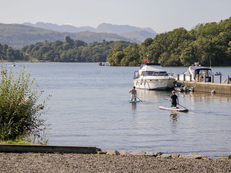 A lake scene with paddleboarders and a boat at 6 Waterside, White Cross Bay, Troutbeck Bridge