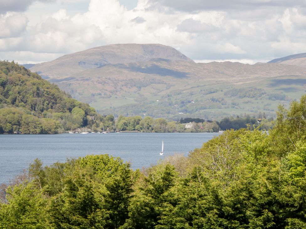A view of a lake with mountains and trees at 6 Waterside, White Cross Bay, Troutbeck Bridge