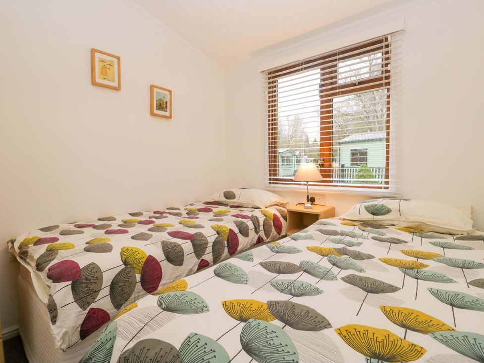 A bedroom with two beds and a bedside table at 6 Waterside, White Cross Bay near Windermere