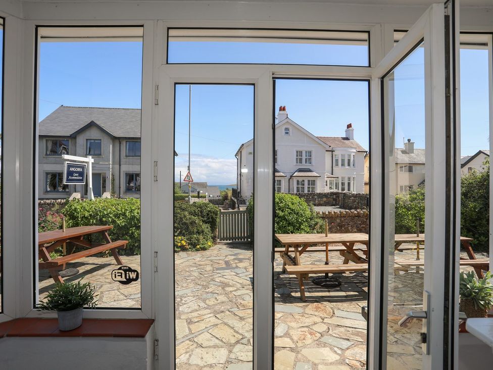 A view from a conservatory showing a table and benches at Angorfa Apartment in Abersoch