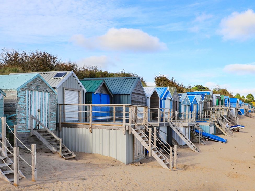 A row of beach huts with stairs on the beach at Angorfa Apartment in Abersoch