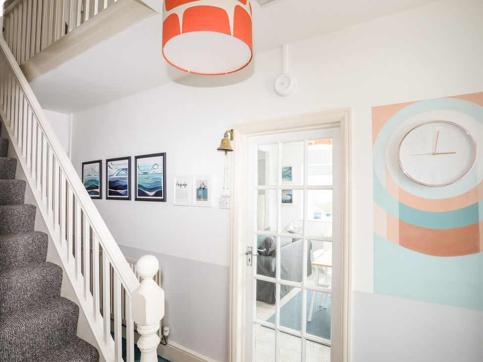 A hallway with a staircase and wall art at Angorfa Apartment in Abersoch