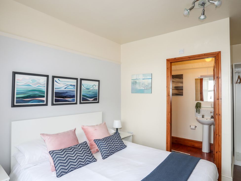 A bedroom with a bed and a doorway to a bathroom at Angorfa Apartment Abersoch