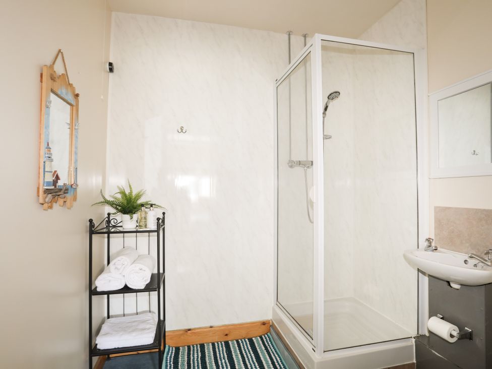 A bathroom with a shower and towels at Angorfa Apartment in Abersoch