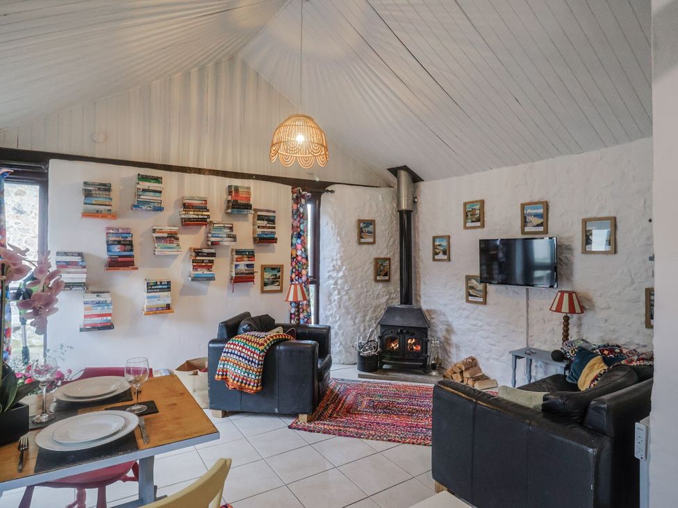 A living room with a fireplace and bookshelf at Honeypot Cottage in Whitchurch Canonicorum