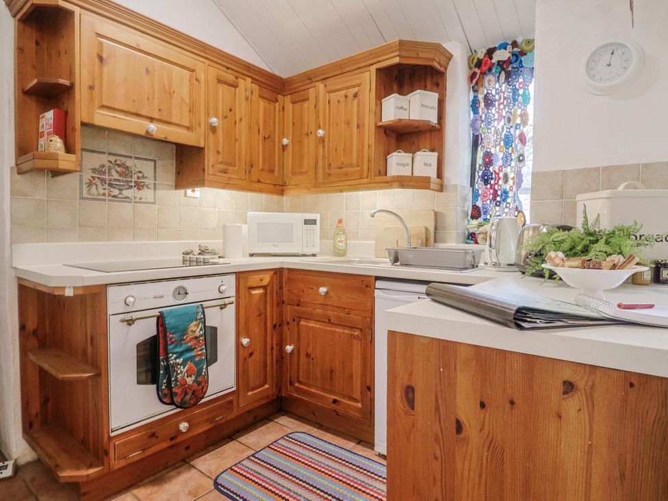 A kitchen with wooden cabinets and appliances at Honeypot Cottage in Whitchurch Canonicorum