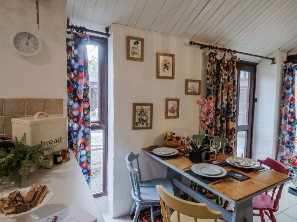 A dining room with a table set with plates and fruit at Honeypot Cottage Whitchurch Canonicorum