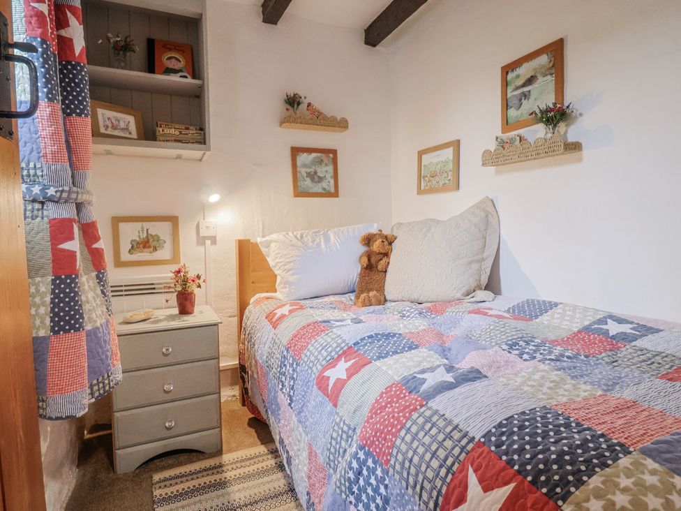 A bedroom with a single bed and a nightstand at Honeypot Cottage Whitchurch Canonicorum