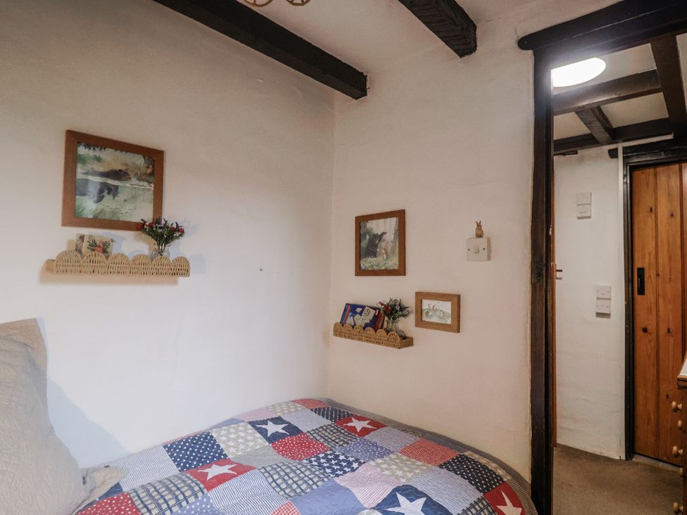 A bedroom with a bed and wall decorations at Honeypot Cottage in Whitchurch Canonicorum