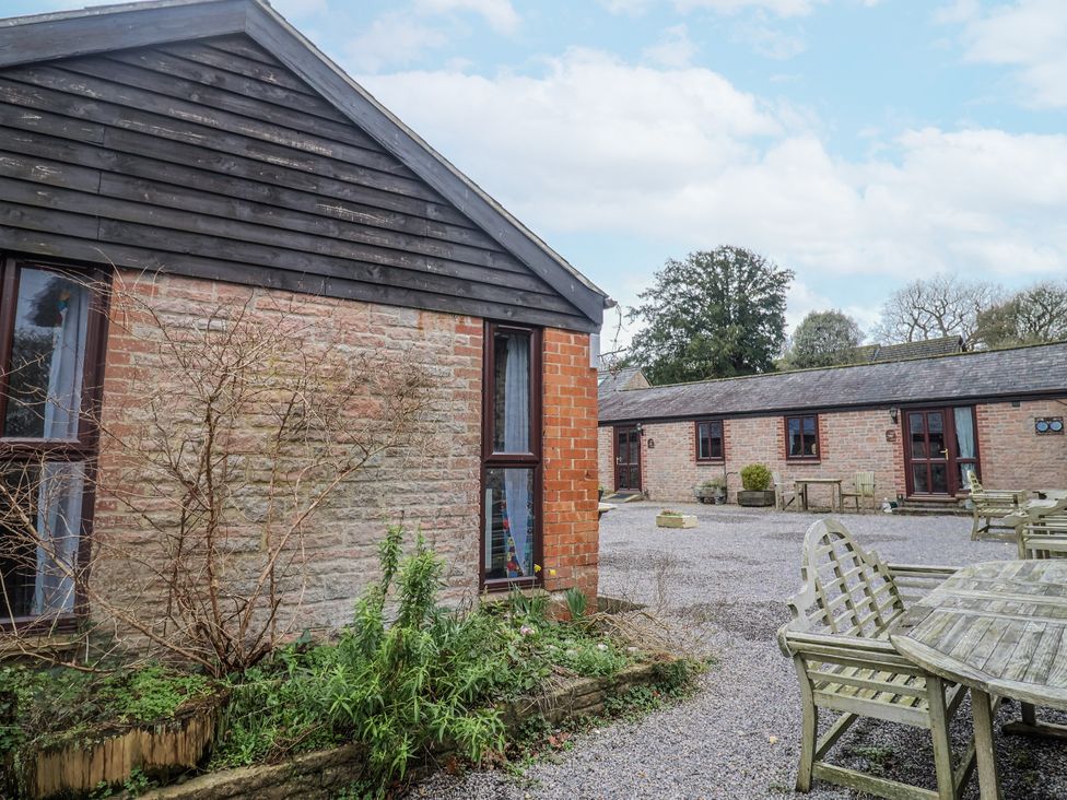 An outdoor area with buildings and seating at Honeypot Cottage Whitchurch Canonicorum
