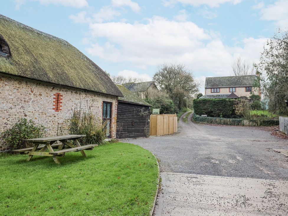 An outdoor area with a stone building and picnic table at Honeypot Cottage in Whitchurch Canonicorum