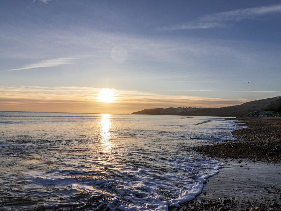 A beach with waves at sunset at Honeypot Cottage Whitchurch Canonicorum