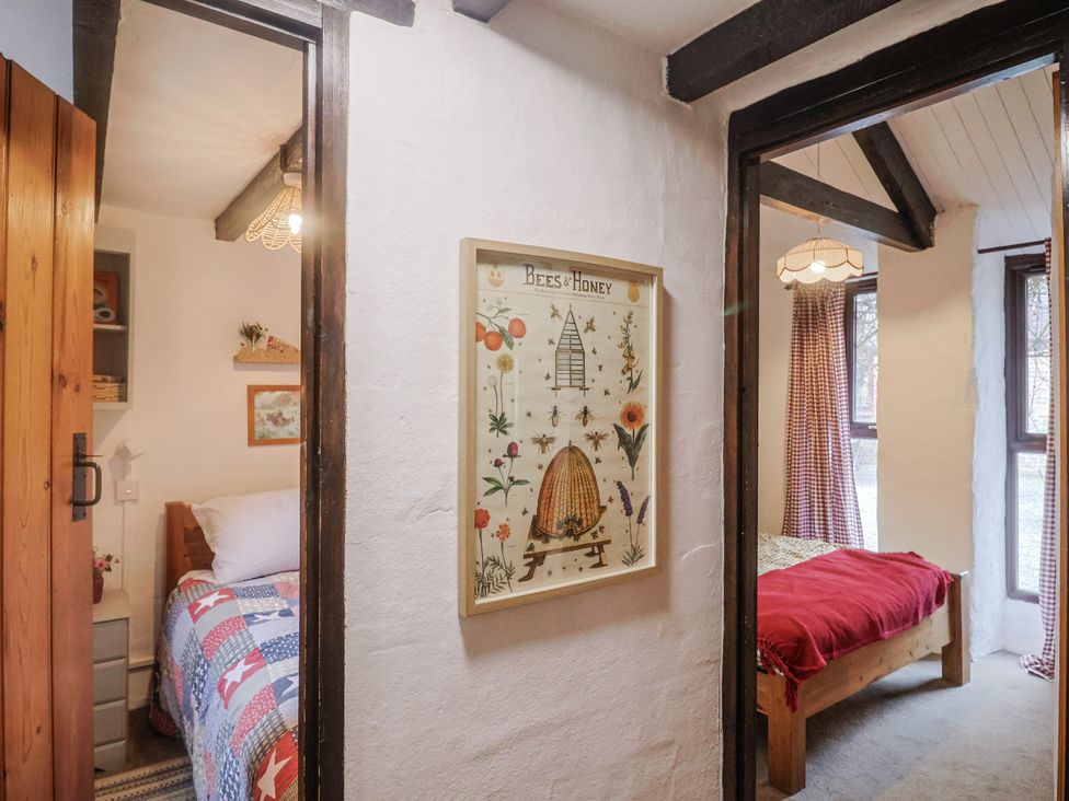 A bedroom with two beds and artwork framed at Honeypot Cottage Whitchurch Canonicorum