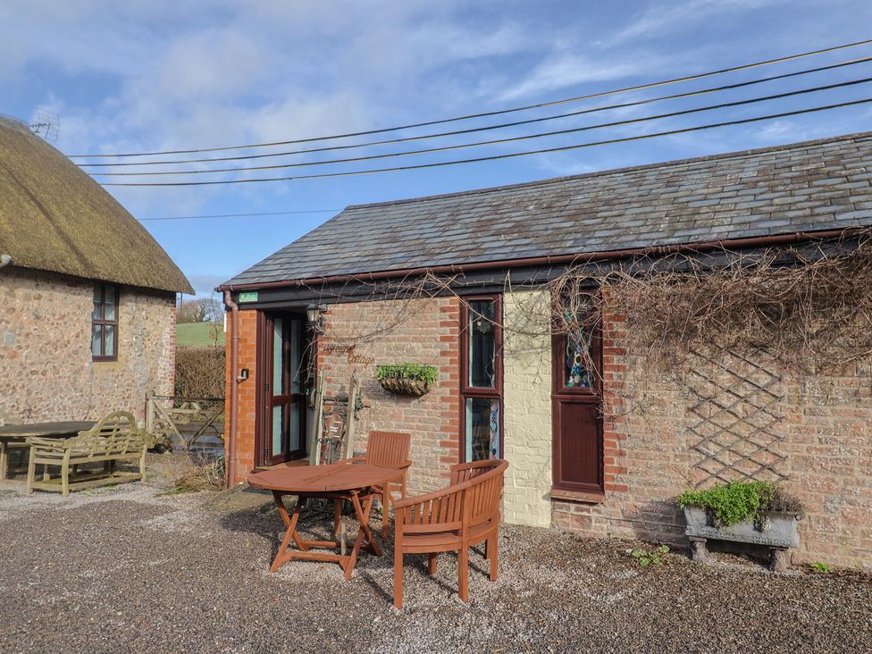 An outdoor seating area with a wooden table and chairs at Honeypot Cottage Whitchurch Canonicorum