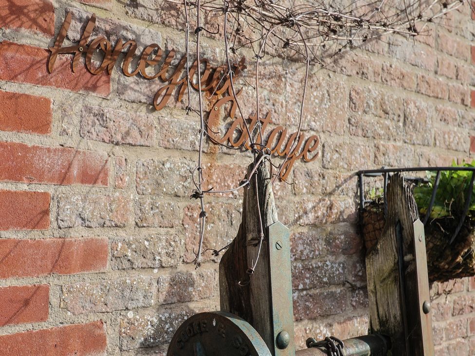 A sign reading Honeypot Cottage on a brick wall at Honeypot Cottage Whitchurch Canonicorum