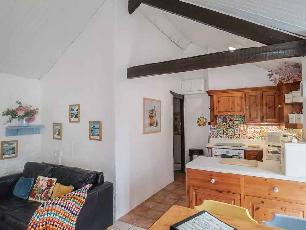 A kitchen with a sofa and wooden kitchen cabinets at Honeypot Cottage Whitchurch Canonicorum