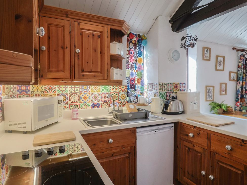 A kitchen with wooden cabinets and appliances at Honeypot Cottage Whitchurch Canonicorum