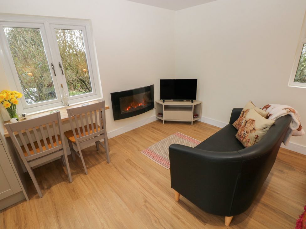A living room with a sofa and dining table at Heidiaway Lodge in Porth