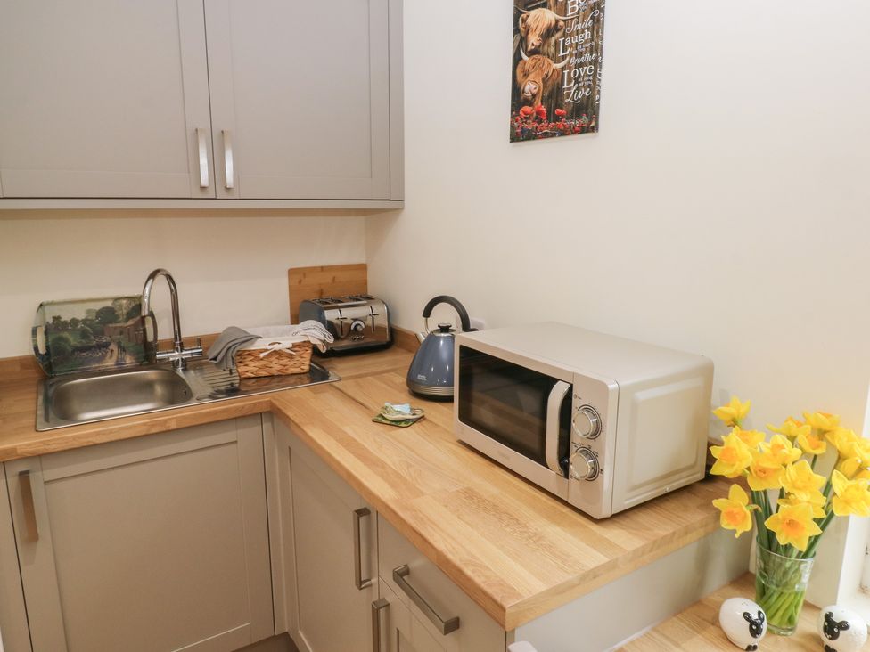A kitchen with a sink, kettle, toaster, and microwave at Heidiaway Lodge, Porth