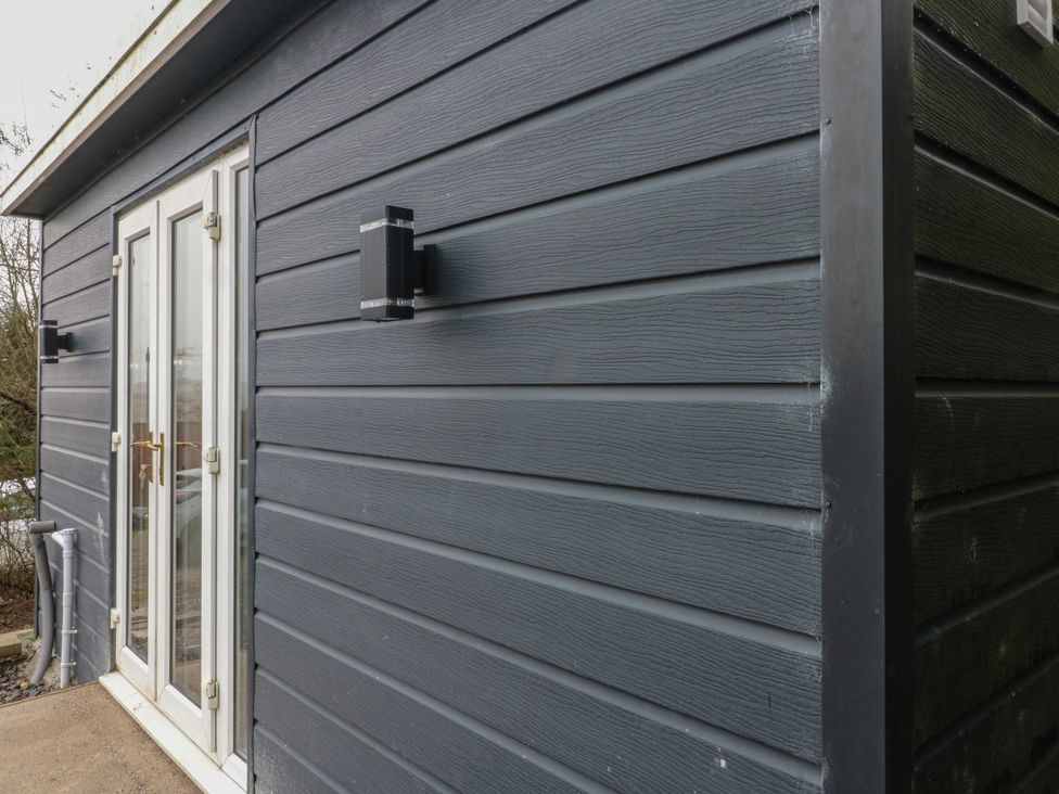 A side view of a building showing an entrance door and light fixtures at Heidiaway Lodge in Porth