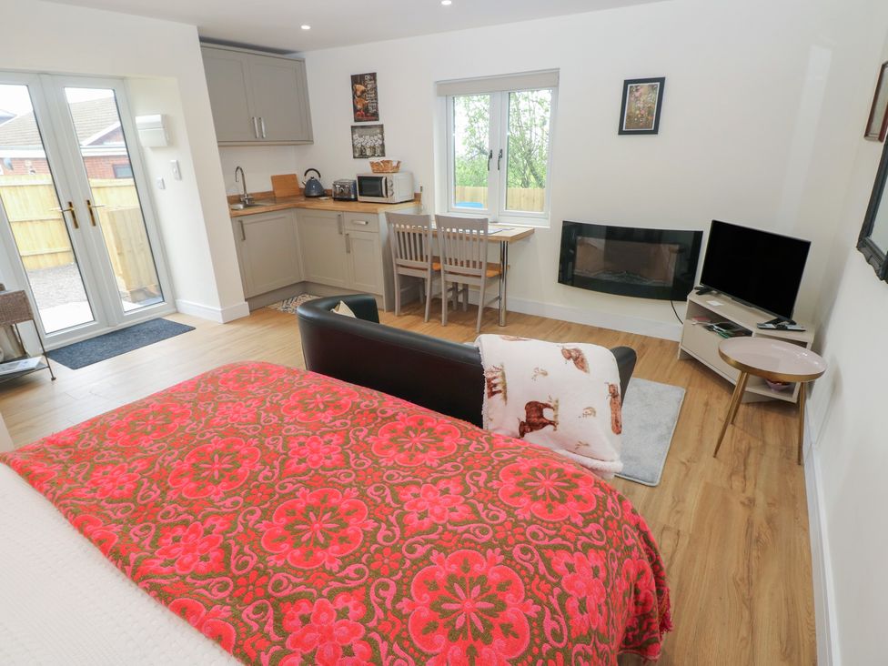 A living room with a kitchenette, dining table and sofa at Heidiaway Lodge in Gilfach Goch