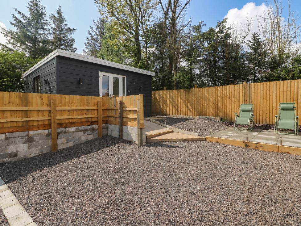 A garden with gravel area and wooden fence at Heidiaway Lodge in Gilfach Goch