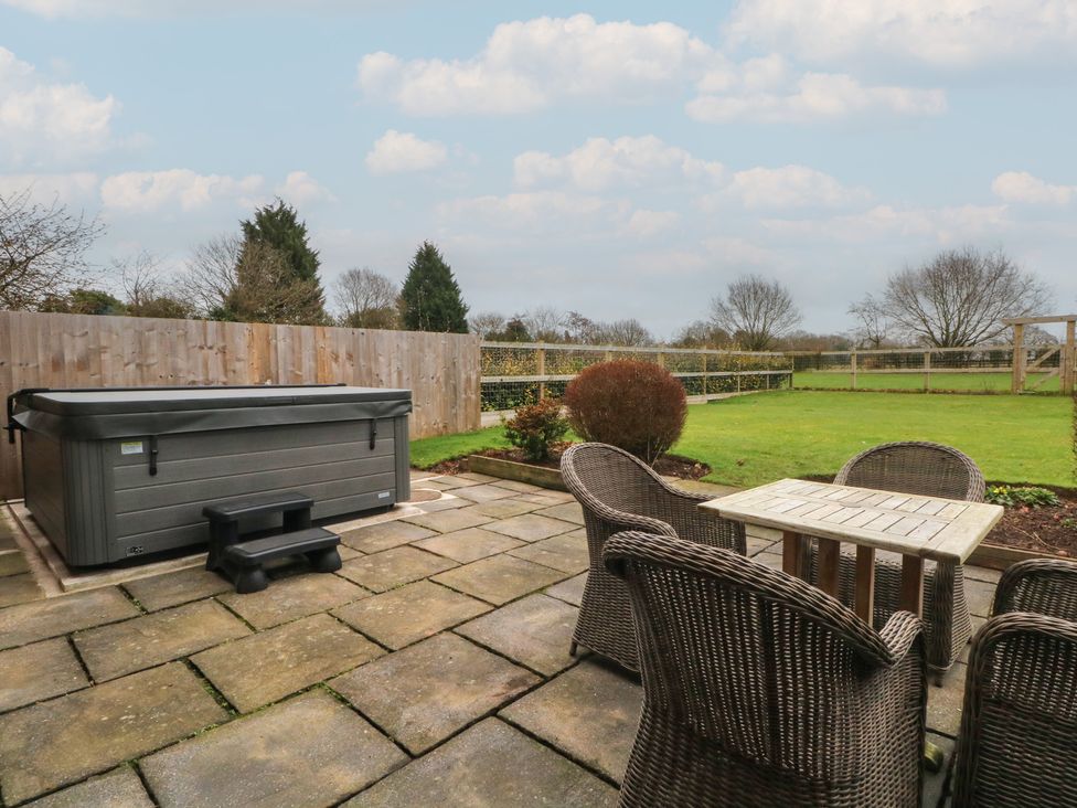 A patio with a hot tub and seating area at The Winnows in Knutsford