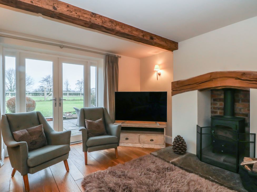 A living room with an armchair and fireplace at The Winnows in Knutsford