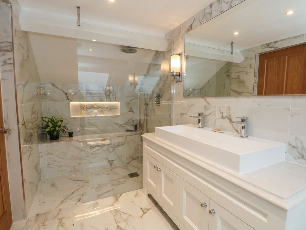 A bathroom featuring a sink with faucet and a shower area at The Winnows in Knutsford