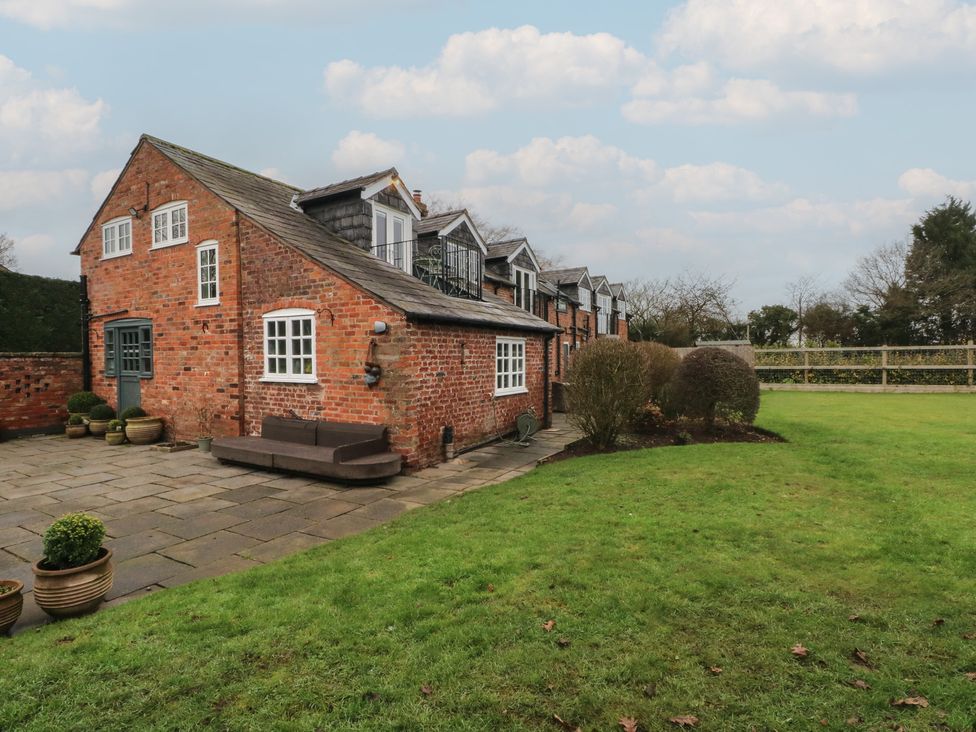 A brick house with a bench and potted plants in the outdoor area at The Winnows in Knutsford