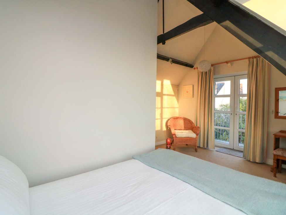 A bedroom with a bed and a chair at Blackstone Cottage Salcombe