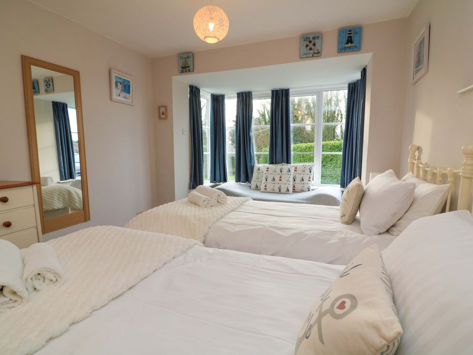 A bedroom with two beds and a window with seating at Blackstone Cottage in Salcombe