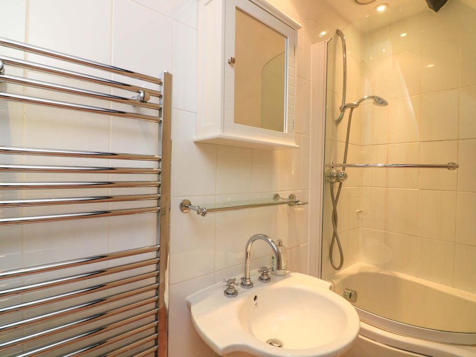 A bathroom with a shower, sink, and mirror at Blackstone Cottage in Salcombe