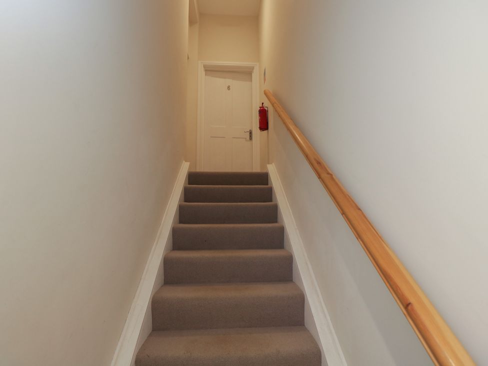A staircase with a door and fire extinguisher at Flat 6
