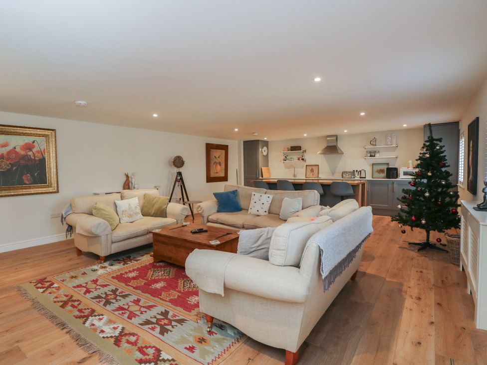 A living room with a sofa and kitchen area at Flat 6