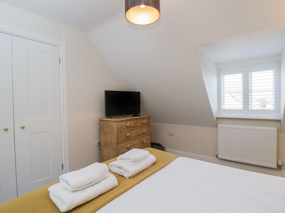 A bedroom with a bed, television, and chest of drawers at Flat 6