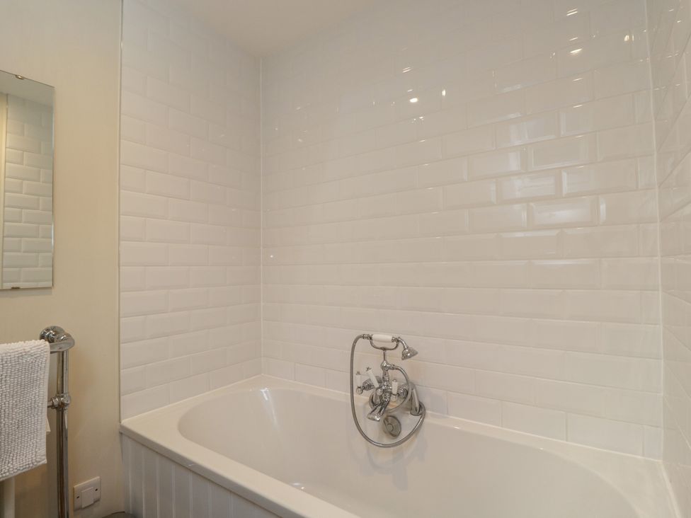 A bathroom with a bathtub and wall tiles at Flat 6