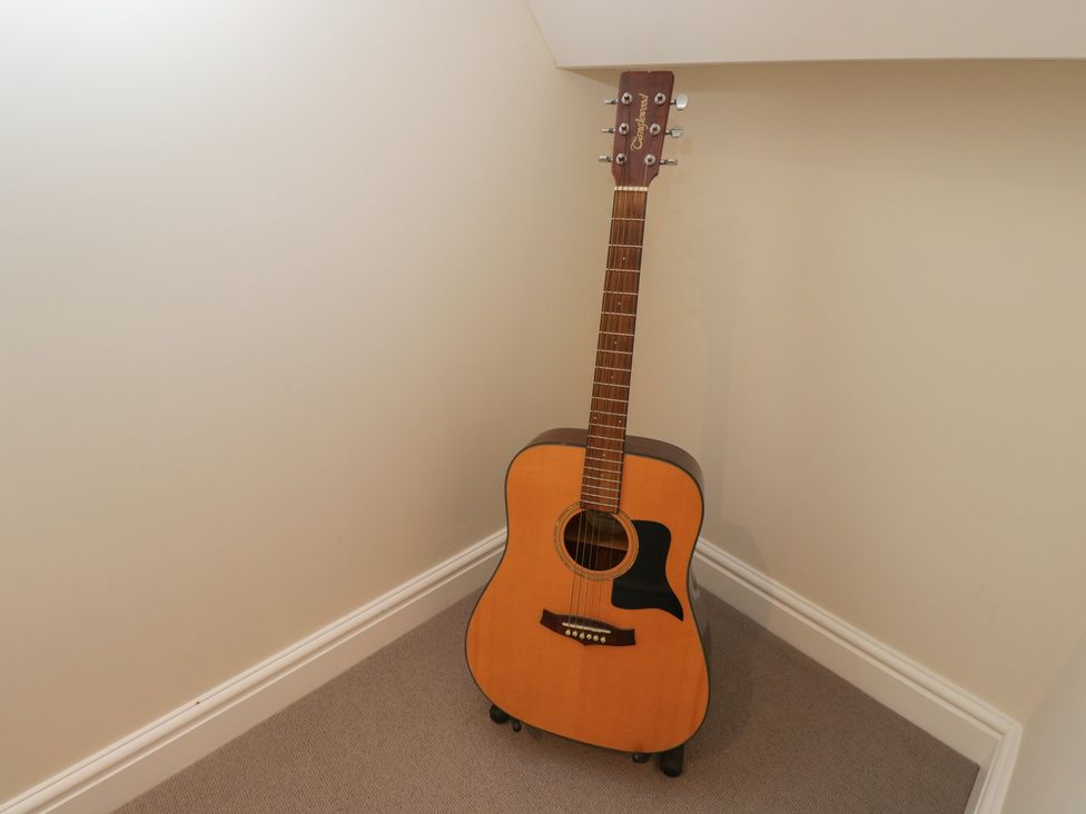 A guitar in a corner of a room at Flat 6 