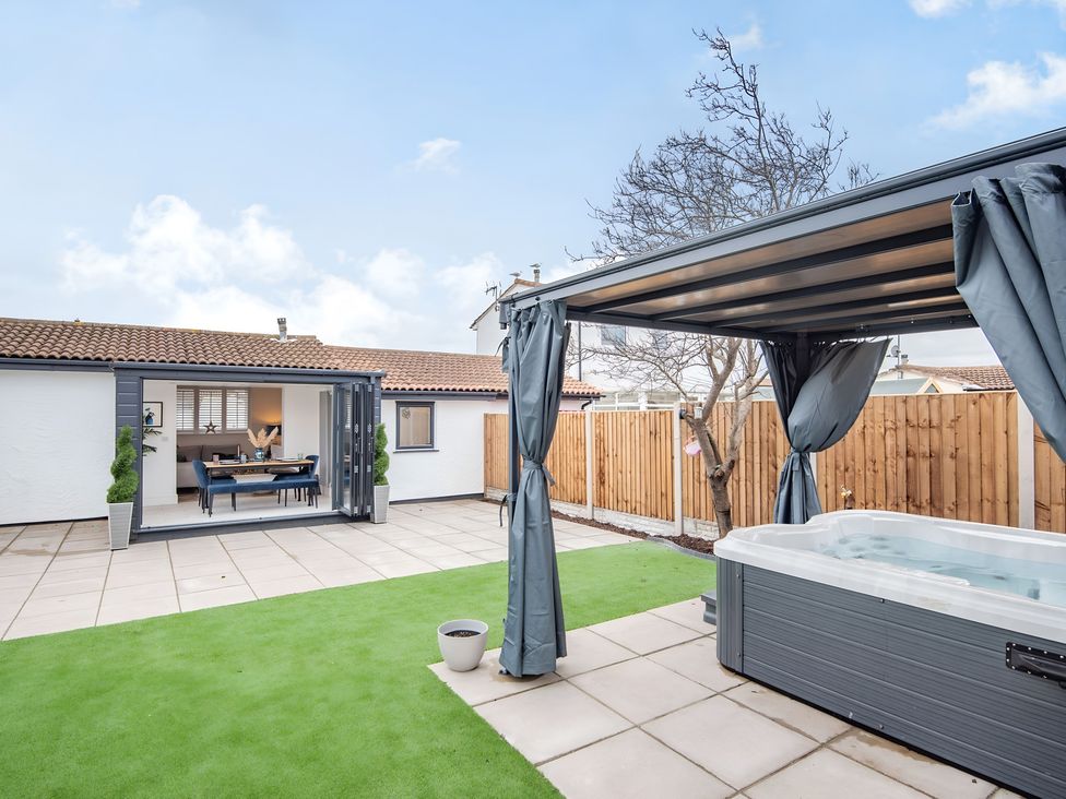 A garden with a hot tub and dining area at 6 Tegafan Abergele