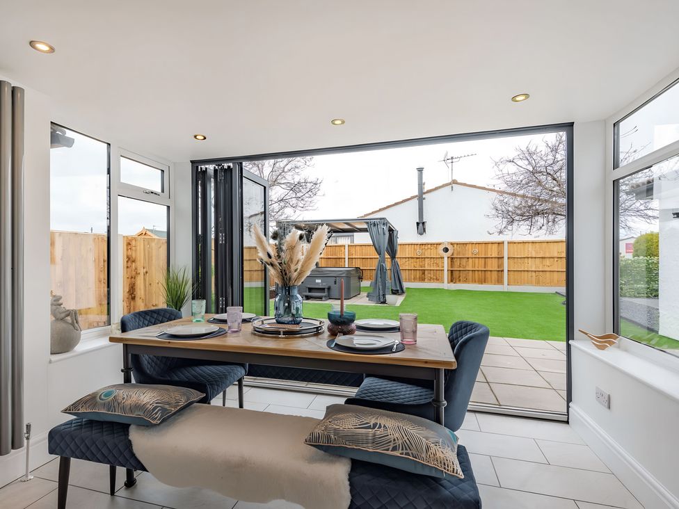 A dining room with a table and chairs overlooking the garden at 6 Tegafan Abergele