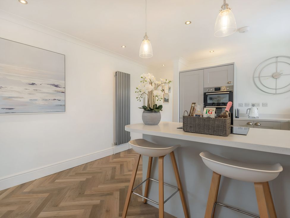 A kitchen with a kitchen island and bar stools at 6 Tegafan Abergele