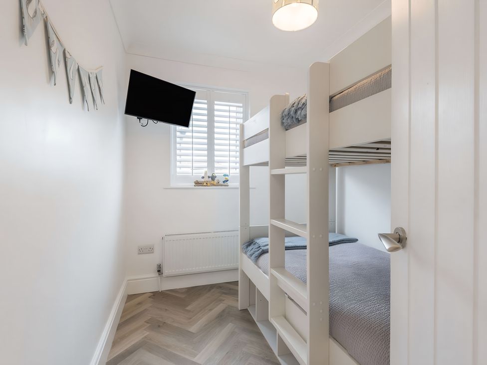 A bedroom with a bunk bed and television at 6 Tegafan Abergele