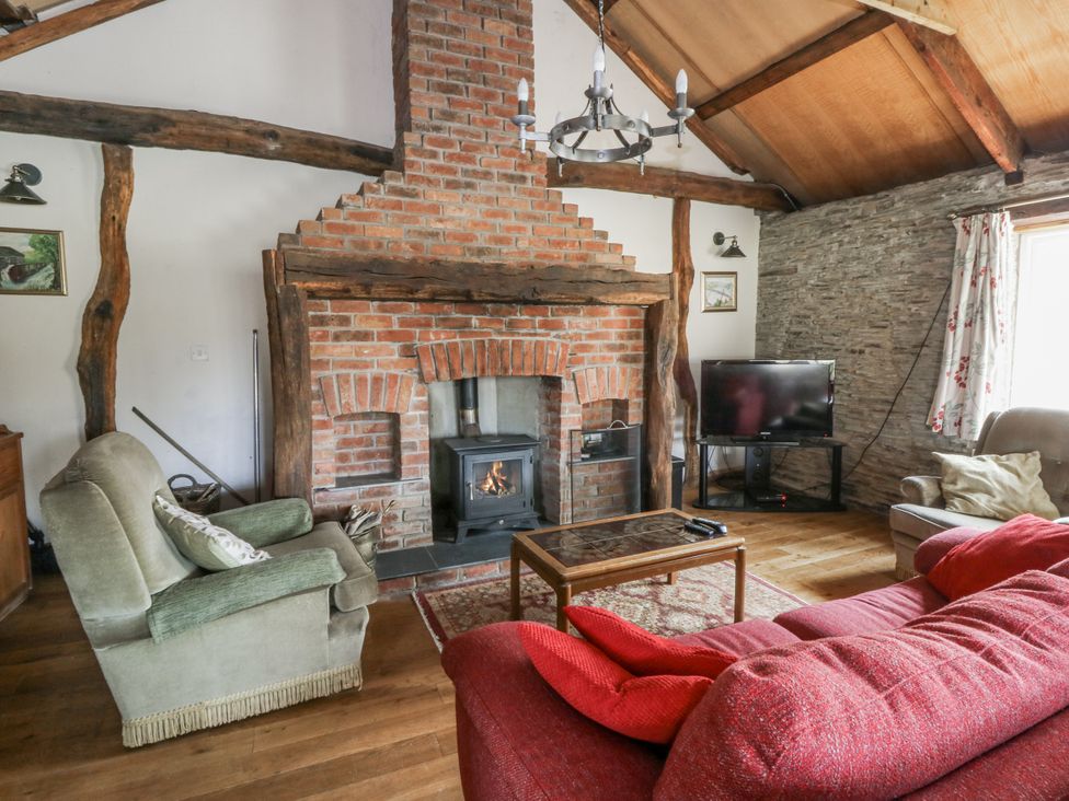 A living room with a fireplace and television at Glanyrafon Smithy in Llandysul