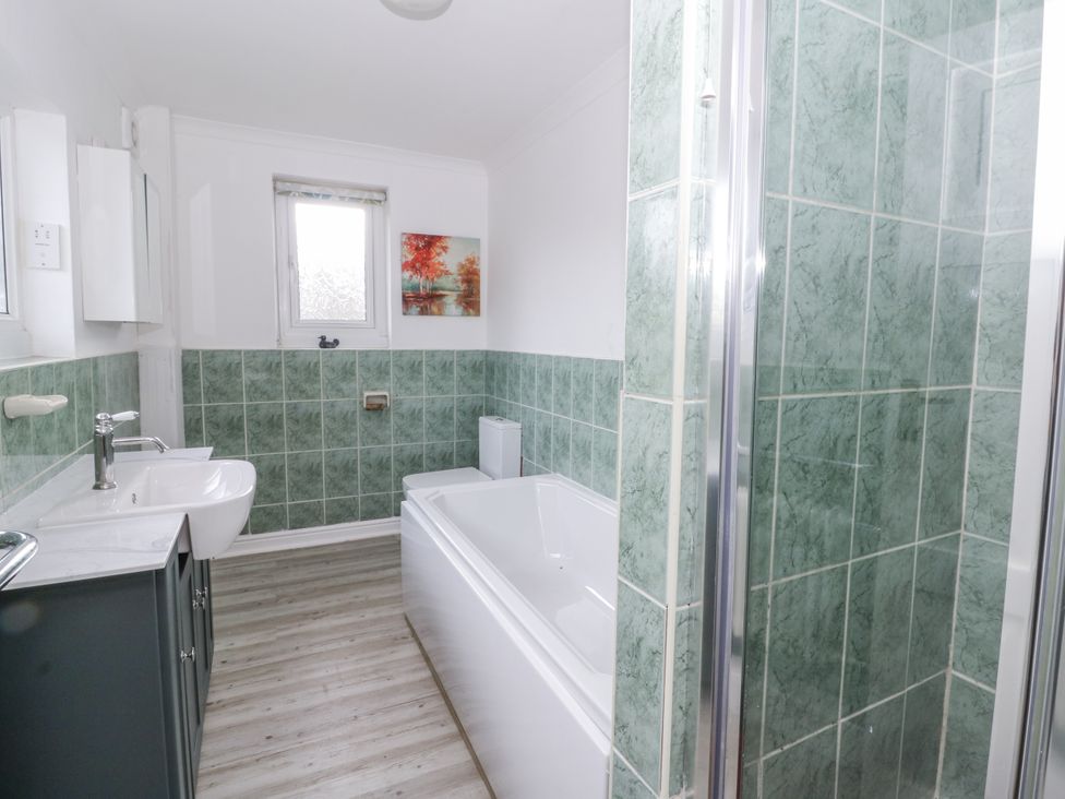 A bathroom with a sink, bathtub, and shower at Glanyrafon Smithy in Llandysul