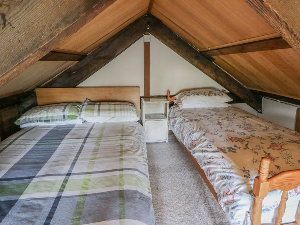 A bedroom with two beds and a bedside table at Glanyrafon Smithy in Llandysul