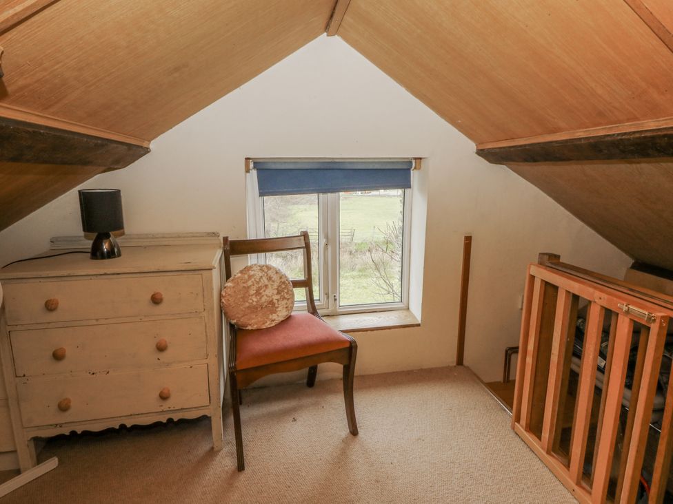 A loft space with a chair and a drawer at Glanyrafon Smithy in Llandysul
