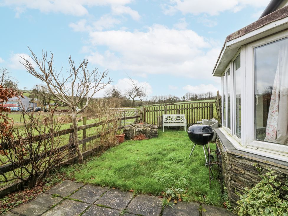 A garden with a bench and barbecue at Glanyrafon Smithy in Llandysul