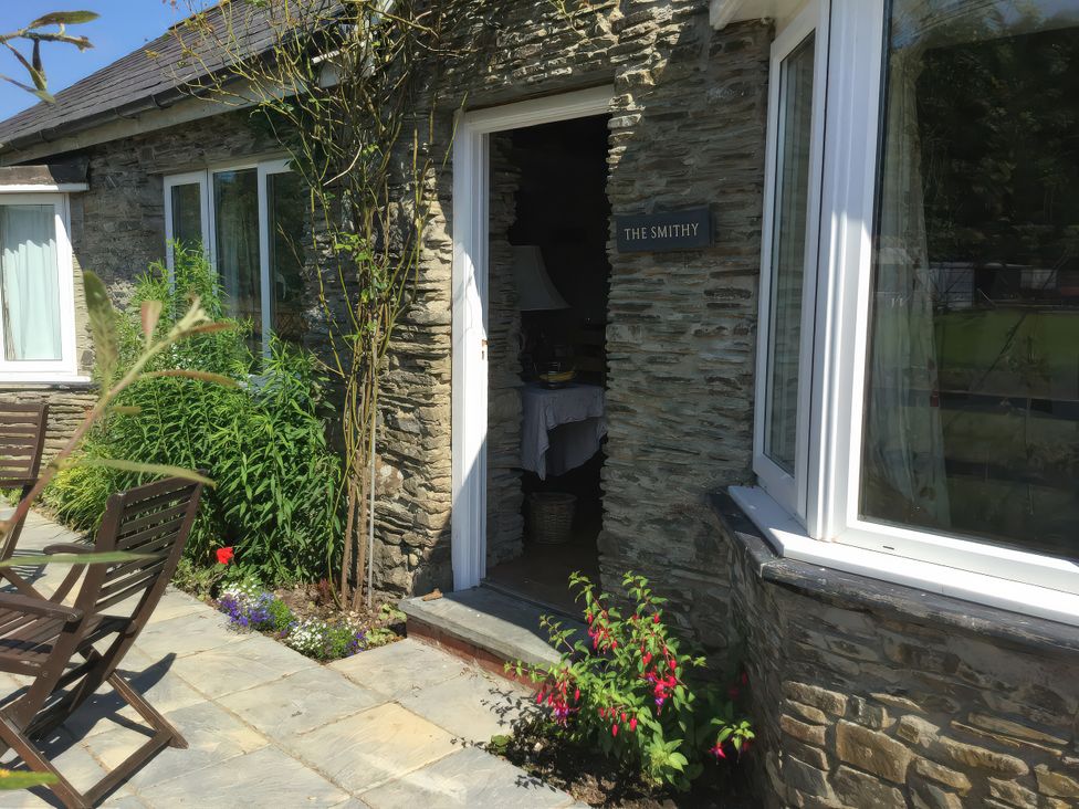 An entrance to a building with a stone wall and patio area at Glanyrafon Smithy New Quay