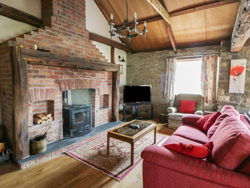 A living room with a fireplace and sofa at Glanyrafon Smithy in New Quay